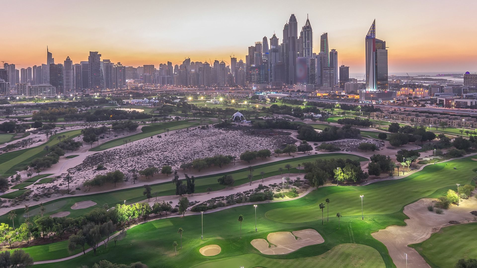Dubai Hills Estate aerial view showing 18-hole championship golf course, Central Park greenery and residential towers with Downtown Dubai skyline visible in background