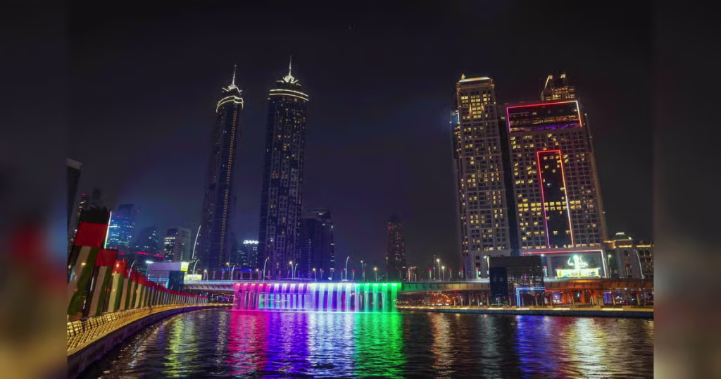 Business Bay Dubai skyline at night featuring the illuminated Dubai Canal waterfall and tower reflections